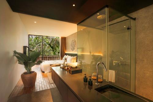 uma casa de banho com um chuveiro e um lavatório com uma banheira em Titik Dua em Ubud
