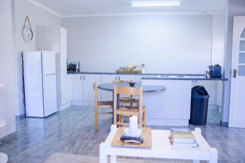 cocina con mesa y nevera blanca en Neat & New Private 2 bedroom Backyard Flat., en Windhoek