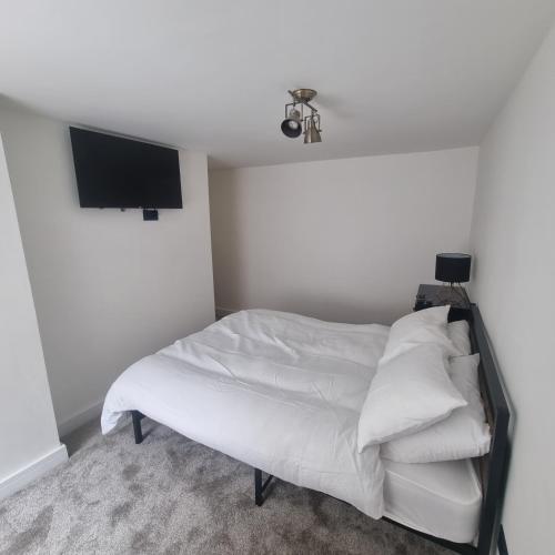 a bedroom with a bed with white sheets and a flat screen tv at Quite central flat in Plymouth