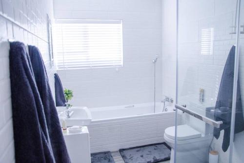 een witte badkamer met een bad, een toilet en een wastafel bij Neat & New Private 2 bedroom Backyard Flat. in Windhoek