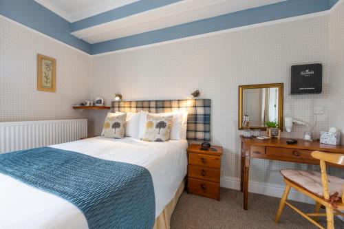 a bedroom with a bed and a desk and a mirror at Edale House B&B in Parkend