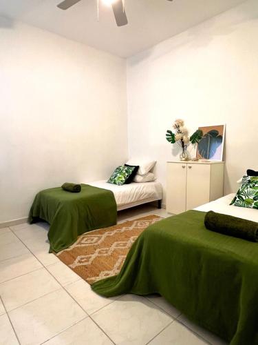 a room with two beds with green sheets and a couch at Top location Sliema stylish rooms in Sliema