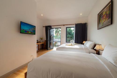 a bedroom with two beds and a tv on the wall at Aurora House in Phu Quoc