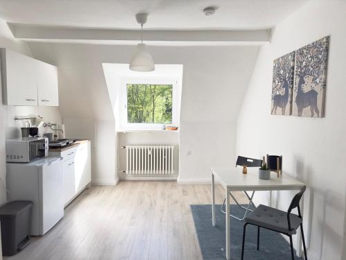 uma cozinha branca com uma mesa e uma janela em Möbliertes Apartment in Bochum-nahe Jahrhunderthalle em Bochum