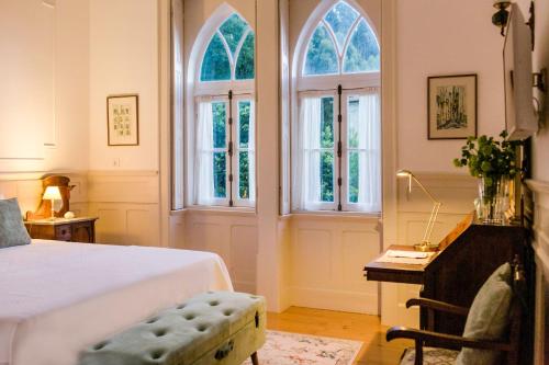 a bedroom with a bed and a desk and windows at Torres da Vila in Anadia
