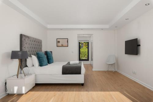 una camera da letto bianca con divano bianco e TV di Kloof Road Luxury Apartments a Città del Capo