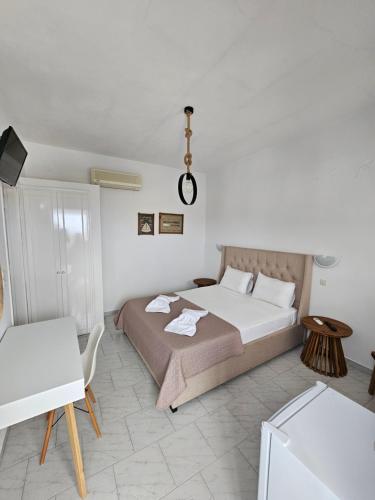 a white bedroom with a bed and a table at ANCHOR in Provatas
