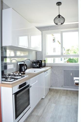 a kitchen with white cabinets and a stove top oven at Pour une agréable pause au Parc ! in Alençon