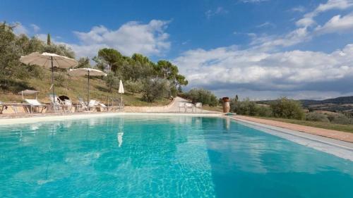 una gran piscina con agua azul y sombrillas en Agriturismo La Margherita, en San Giorgio Scarampi