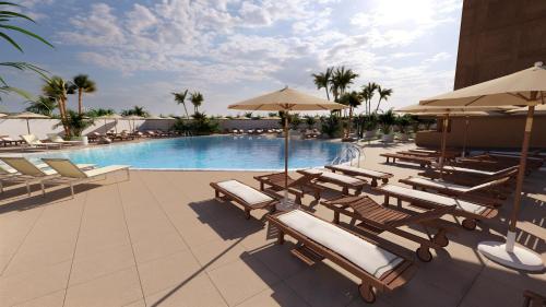 una piscina con tumbonas y sombrillas en AluaSoul Costa Adeje, en Adeje