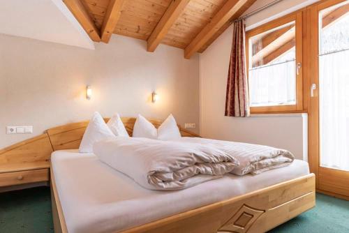 a bedroom with a bed with white sheets and a window at Edelweiss Ladis im Sommer inklusive Super Sommer Card in Ladis