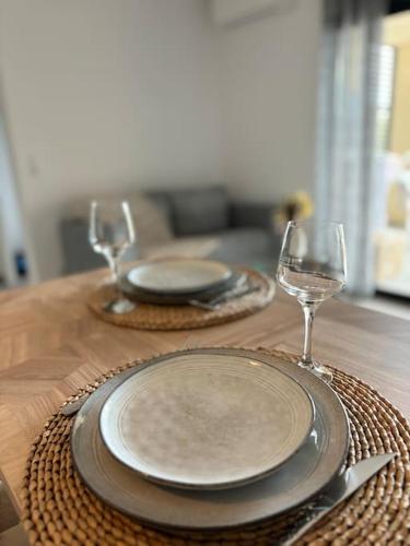 - une table en bois avec 2 assiettes et des verres à vin dans l'établissement Charmant appartement T2 neuf, à Porto-Vecchio