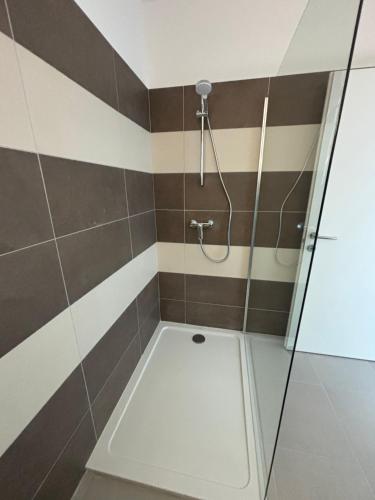 La salle de bains est pourvue d'une douche avec des rayures brunes et blanches. dans l'établissement Charmant appartement T2 neuf, à Porto-Vecchio