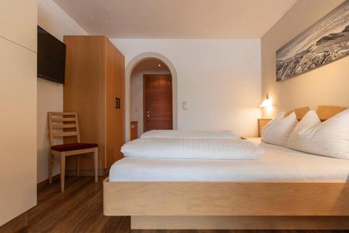 a hotel room with two beds and a chair at EDELWEISS Ladis in Ladis