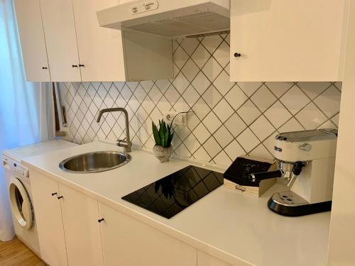 una cucina bianca con lavandino e piano di lavoro di City Apartment Acqui Terme ad Acqui Terme