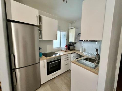 a kitchen with white cabinets and a stainless steel refrigerator at Céntrico apartamento bien ubicado para 5, 3 Hab in Alcobendas