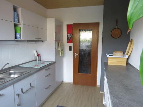 uma cozinha com armários brancos e uma porta castanha em Ferienwohnung Mia em Tirschenreuth