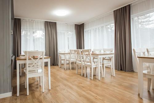 a dining room with white tables and chairs and windows at Willa Klonowa in Wisła