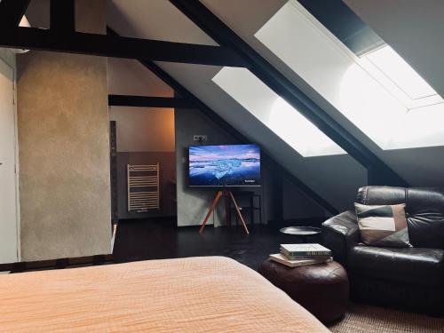 a attic room with a bed and a tv at La Grainerie in Durbuy