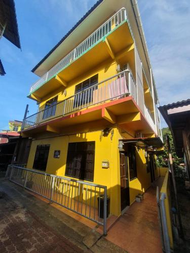 a yellow building with a balcony on the side of it at JV Inn Perhentian in Kampong Pasir Hantu