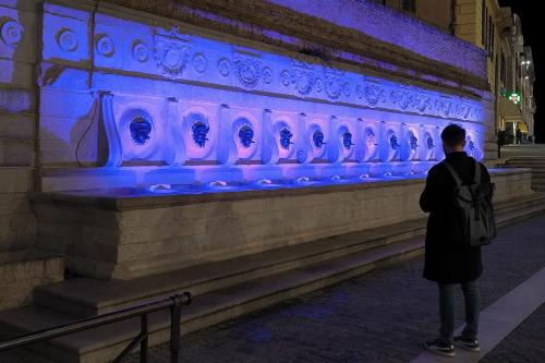 un hombre parado frente a una pared con luces azules en Palombeach en Ancona