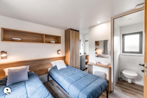 a small room with two beds and a bathroom at Camping Les Violettes in La Faute-sur-Mer