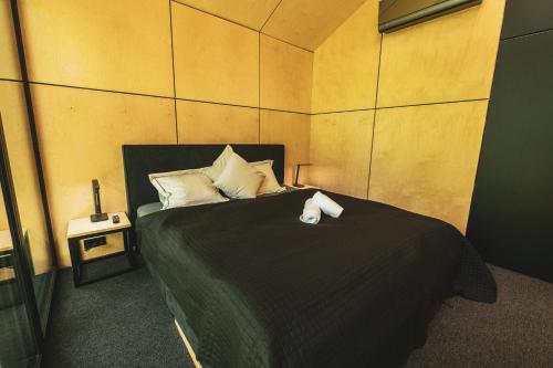 a bedroom with a bed with a black blanket and white pillows at LagomHome Luxus Pihenőház ***** Noszvaj in Noszvaj
