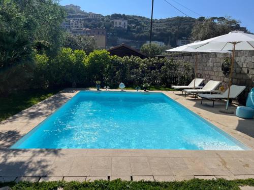a blue swimming pool with chairs and an umbrella at Suite Lidia B&B in Sorrento