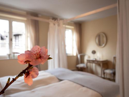 a branch with pink flowers sitting on a bed at REFUGIUM Theresienstraße 19 - Chambre Morisot in Rhodt unter Rietburg