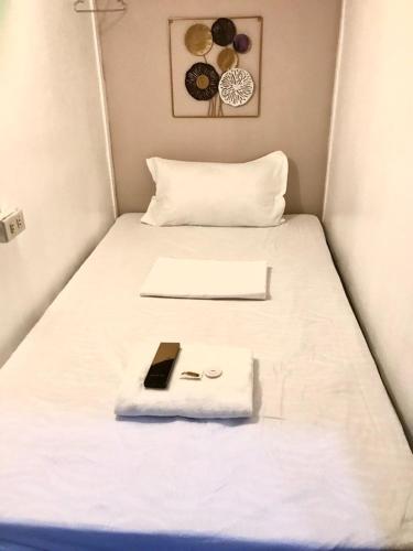 a bed in a small room with a cell phone on it at Budget Transient Capsule Room Mirasol Near BGC in Manila