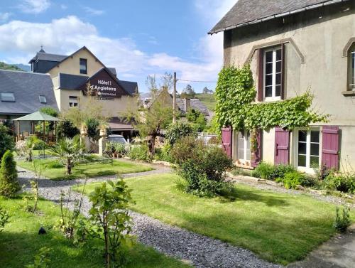 un jardin en face d'un bâtiment avec une maison dans l'établissement L'ancien Hôtel du vieux Cèdre, à Arreau