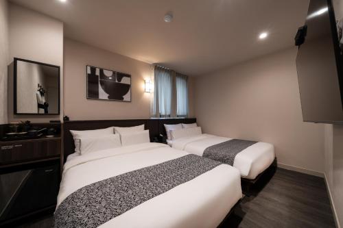 Cette chambre comprend deux lits et une télévision. dans l'établissement AANK Ryokan Hotel Paju, à Paju