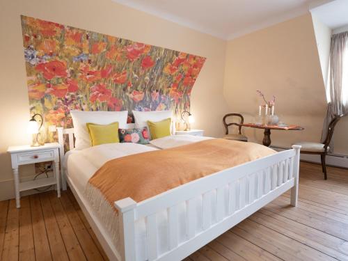 a bedroom with a large white bed with a painting on the wall at REFUGIUM Theresienstraße 19 - Chambre Vonnoh in Rhodt unter Rietburg