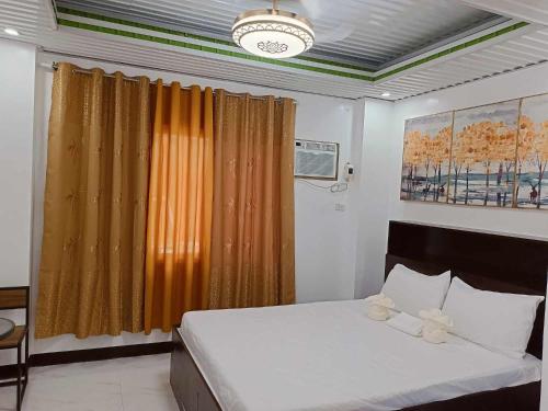 a bedroom with a bed with an orange curtain at KMJ SUITES in General Luna