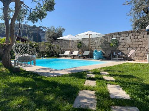 a swimming pool in a yard next to a stone wall at Chalet Lidia in Sorrento