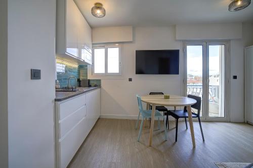 Il comprend une cuisine avec une table et des chaises ainsi qu'une télévision. dans l'établissement Magnifique studio Le Dauphin 50m des plages, à Juan-les-Pins
