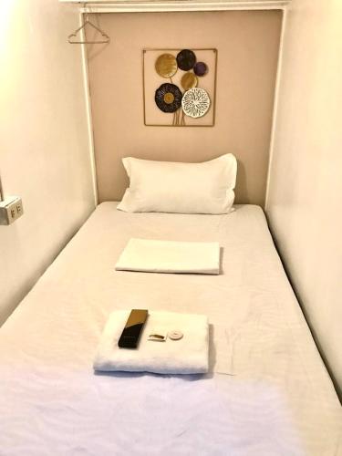 a bed with a white blanket and a book on it at Budget Transient Capsule Room Mirasol Near BGC in Manila