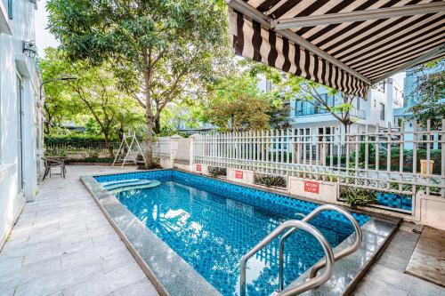 a swimming pool with an umbrella next to a building at Villa FLC Sầm Sơn SH20 in Sầm Sơn