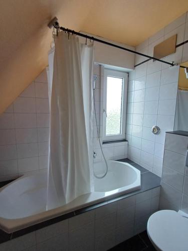 a white tub in a bathroom with a shower at B&B Koeln Zuendorf in Cologne