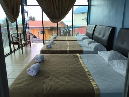a row of beds in a room with large windows at JV Inn Perhentian in Kampong Pasir Hantu