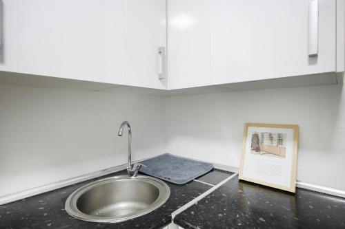 fregadero en una cocina con una foto en la encimera en Apartamento tres habitaciones en Nou Barris by Alterhome, en Barcelona