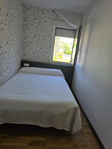 a small bedroom with a bed and a window at Noja Rooms in O Pedrouzo