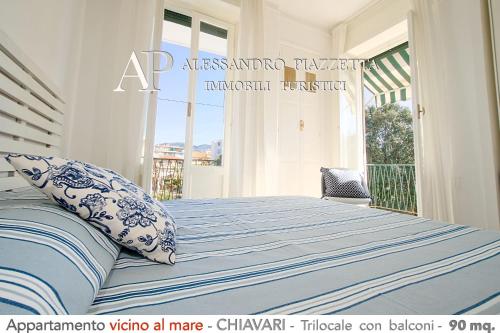 a bedroom with a bed with blue and white sheets and a window at Dolce Mare in Chiavari