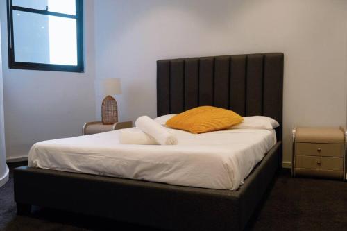 a bed with a yellow pillow on top of it at Newtown 2Br near station & shops in Sydney