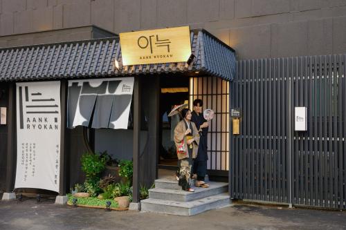 dos personas parados frente a una tienda en AANK Ryokan Hotel Paju, en Paju