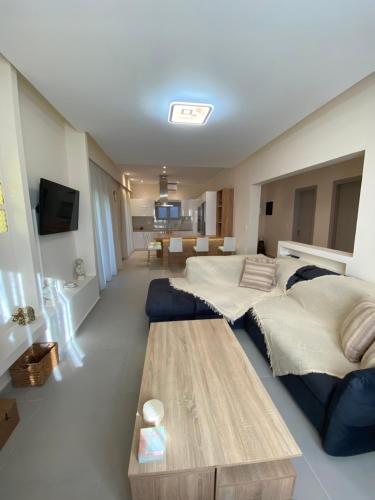 uma sala de estar com 2 camas e uma mesa de madeira em Olea House 2' walk from the sea em Nótos
