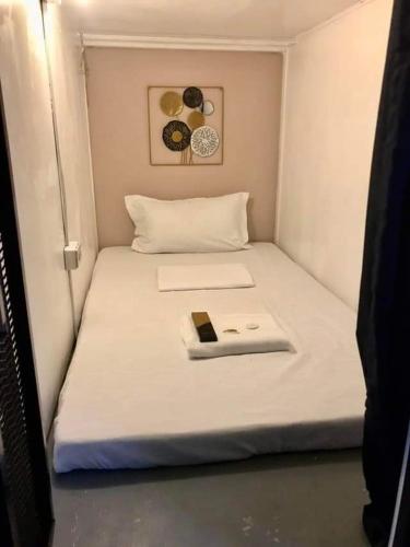 a small white bed with a book on it at Budget Transient Capsule Room Mirasol Near BGC in Manila