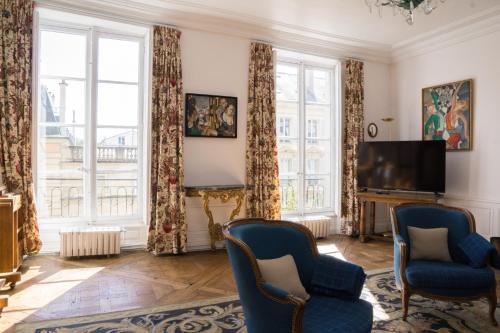 uma sala de estar com 2 cadeiras e uma televisão de ecrã plano em Magnifique appartement au coeur de Versailles em Versailles