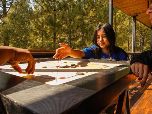 a woman sitting at a table playing a board game at THEHIMALAYANLIVING WHISTLING PINES in Mukteswar