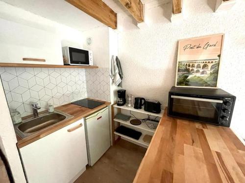 a small kitchen with a sink and a microwave at Duplex - A 2 pas des Arènes in Nîmes